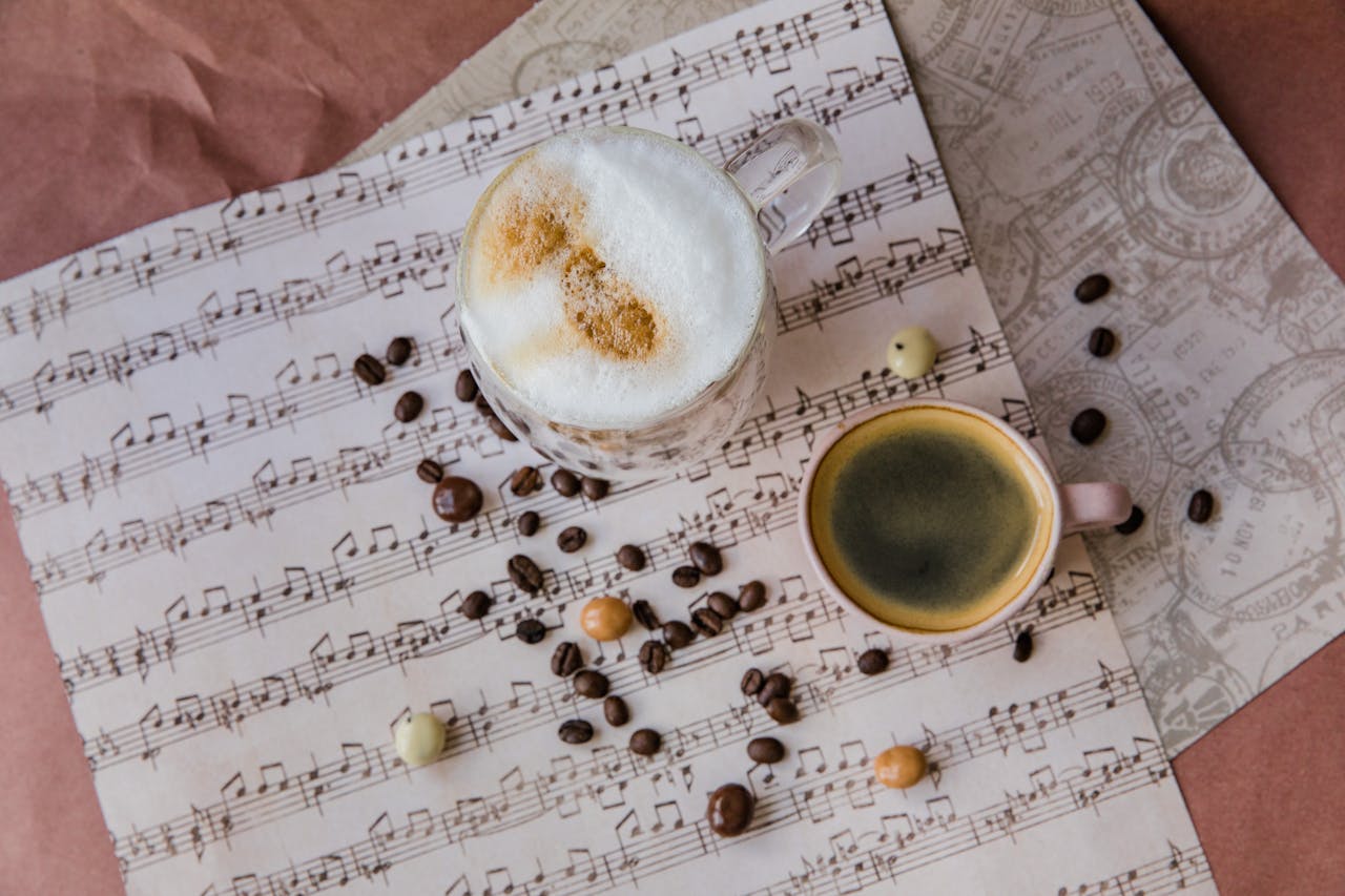 Creative flat lay of coffee cups and beans on music sheet for a cozy ambiance.